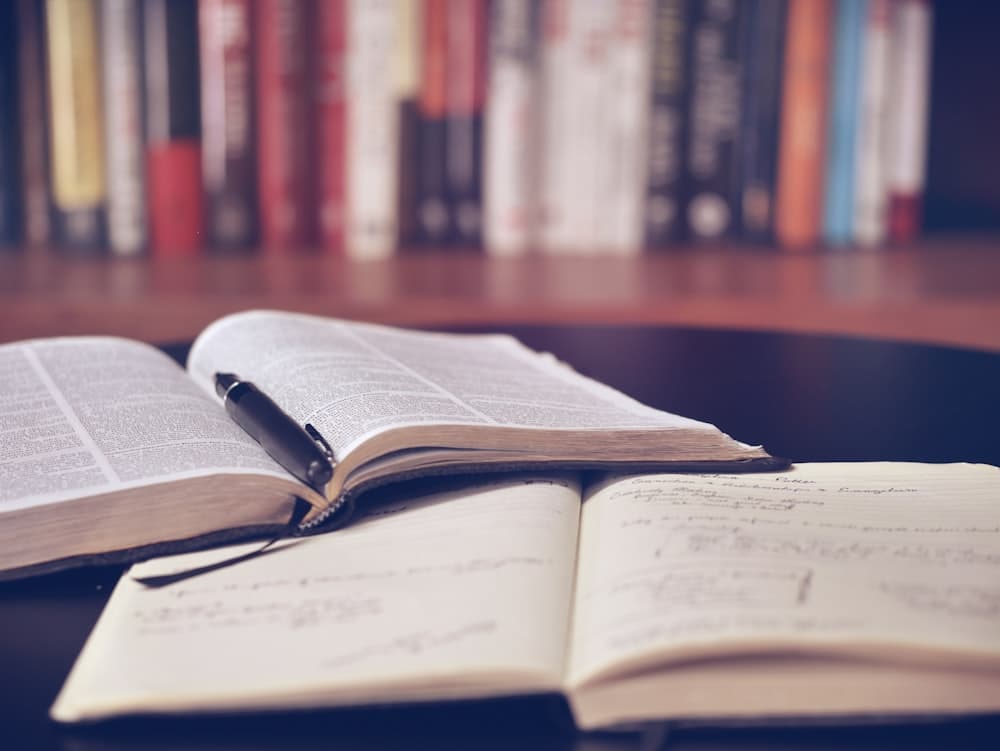 Open boek en notitieboek met aantekeningen op een bureau